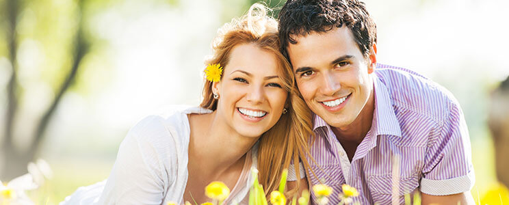 a young couple in a field of flowers smiling