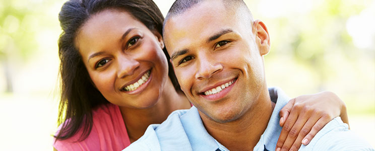 a young couple smiling with a forest in the background